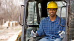 A man smiles while sitting in a skidsteer.